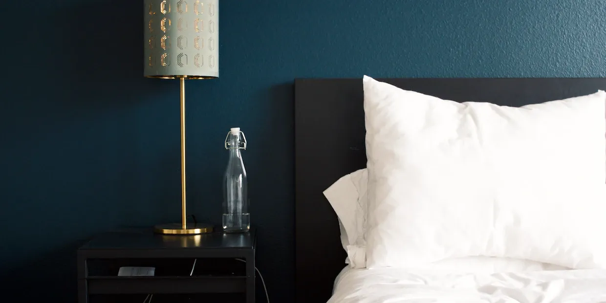 A plump white down pillow resting against a tufted headboard on a freshly made bed