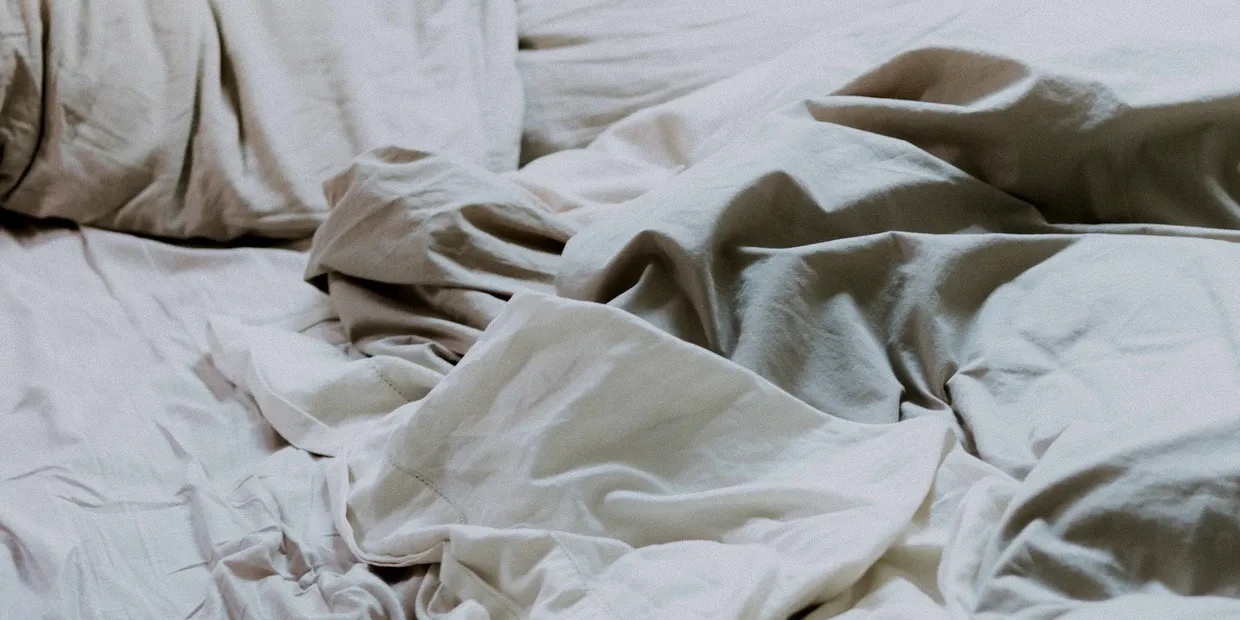 A foam wedge pillow propped against a headboard on a neatly made bed
